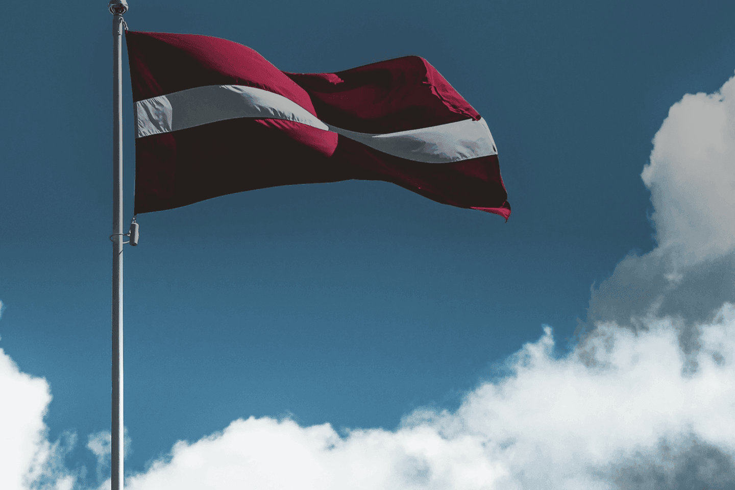 Better Flags | CiCLO Flags | Latvian flag waving on a flagpole against a blue sky