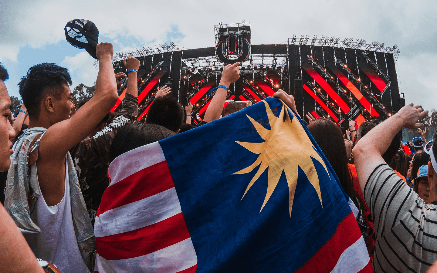 Publiek bij een festivalpodium in de openlucht houdt een vlag omhoog