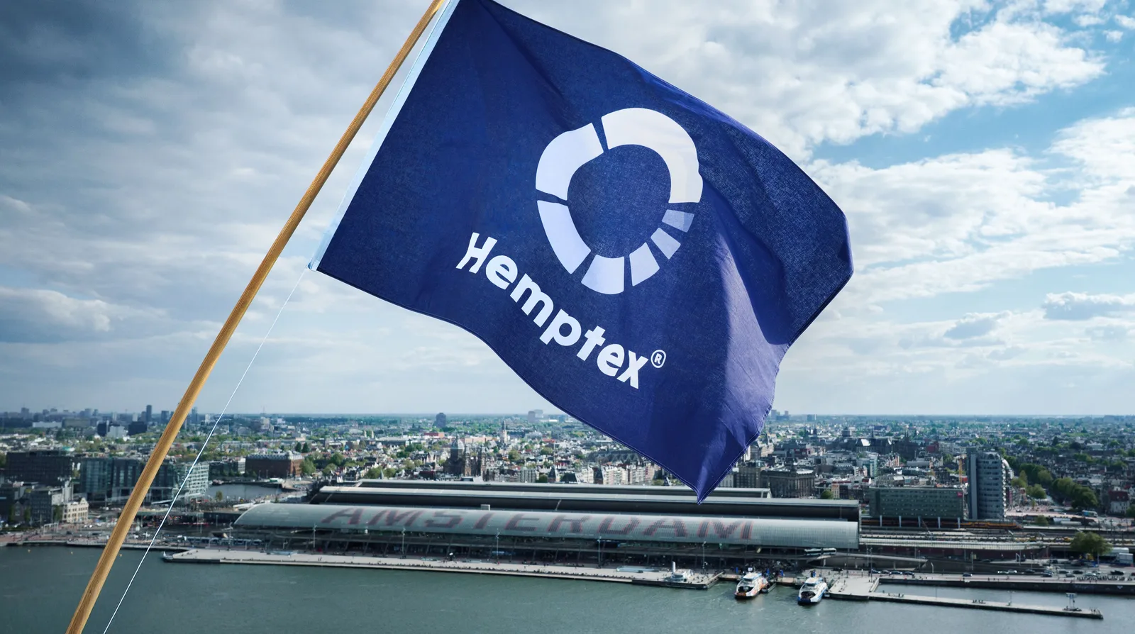 Navy Hemptex® mast flag flying from an angled wooden mast high above Amsterdam Centraal and the IJ waterfront