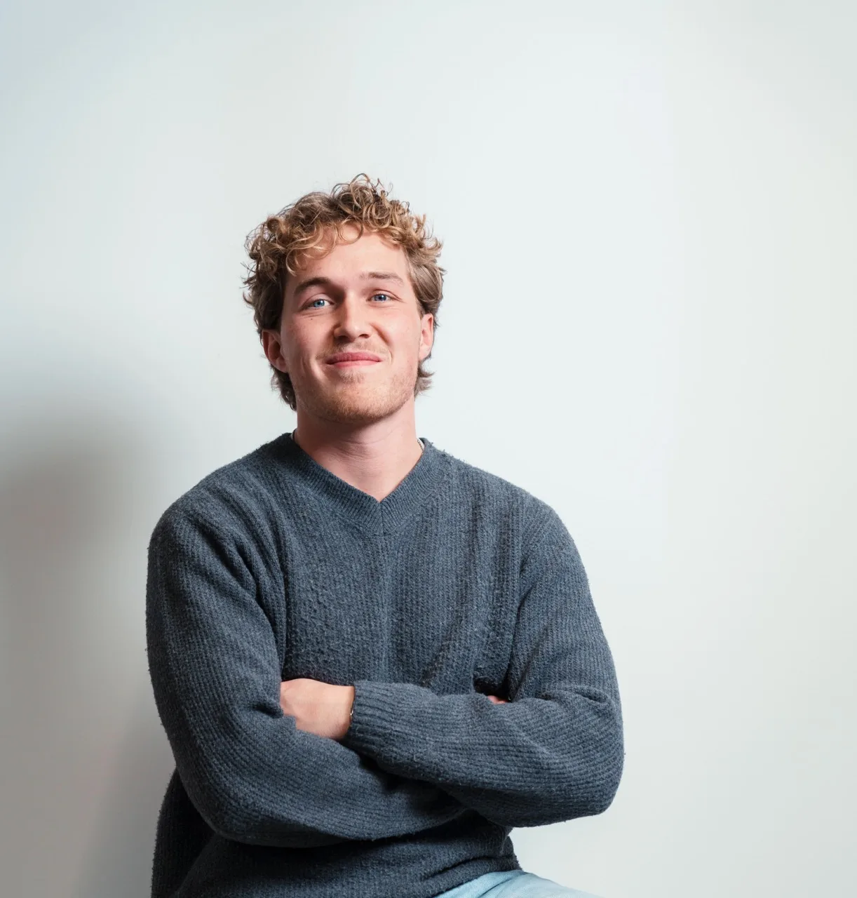 Niek van der Kuijl, founder of Better Flags, smiling with his arms folded, in a grey jumper against a white wall